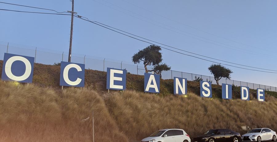 Large white-on-blue OCEANSIDE letters on a grassy slope at Oceanside Harbor