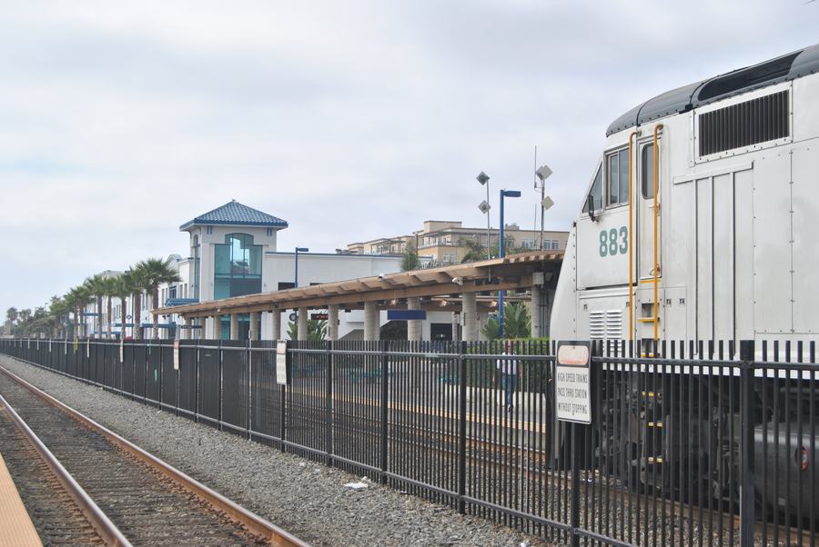 Platform and station building of Oceanside Transit Center with a Metrolink locomotive at the right