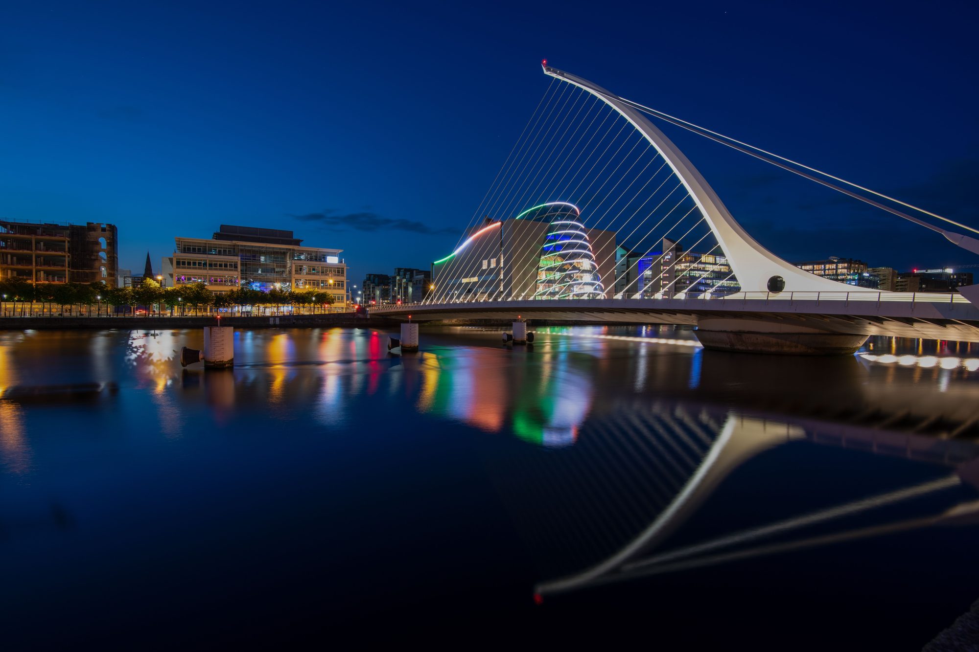 The Samuel Beckett Bridge lit at dusk over the River Liffey, with the Convention Centre behind it.