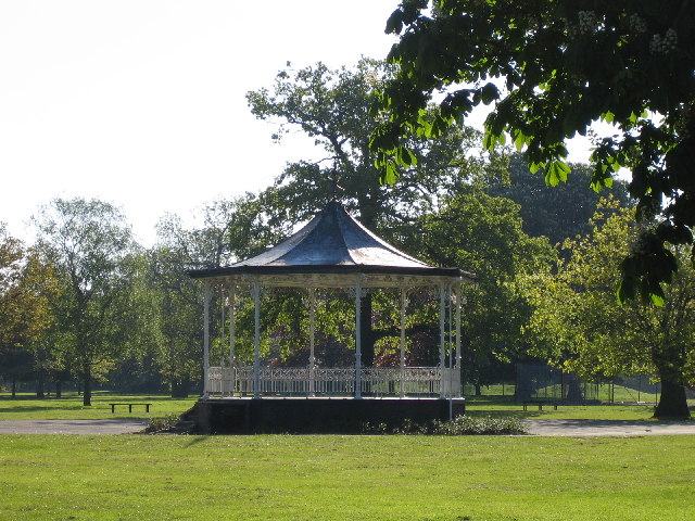A cast-iron bandstand with a dark roof standing among trees in Barra Hall Park in 2005