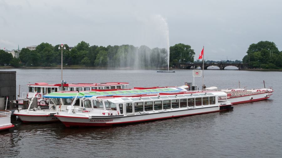 Sightseeing boats moored on the Binnenalster with the lake's fountain playing behind them