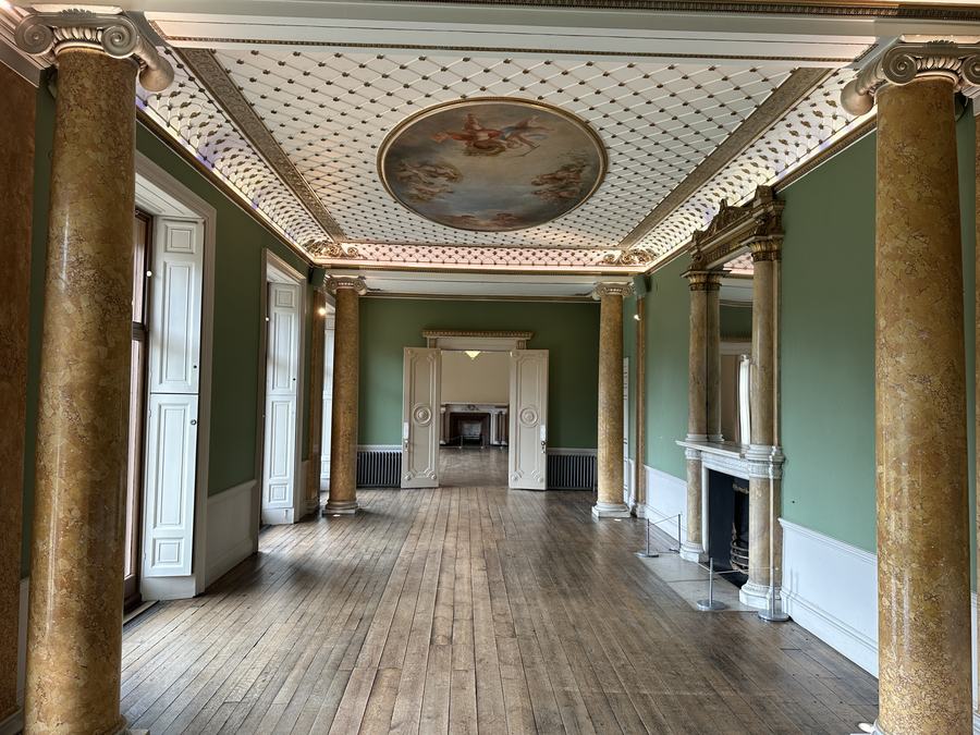 The green-walled Long Gallery inside the Large Mansion, with marbled columns and a painted ceiling roundel