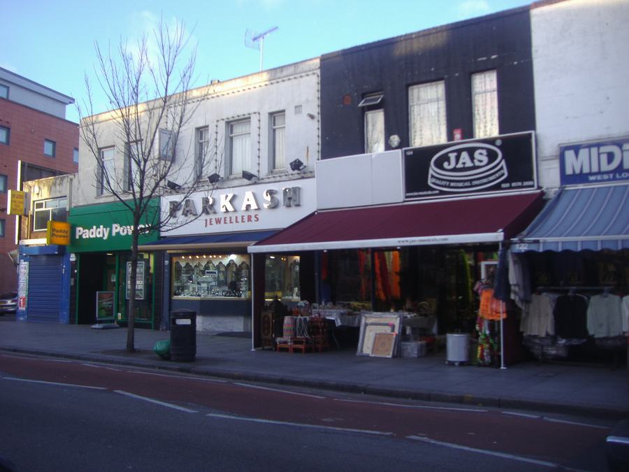 A parade of shops on Southall Broadway, jewellers and clothing shops with awnings out