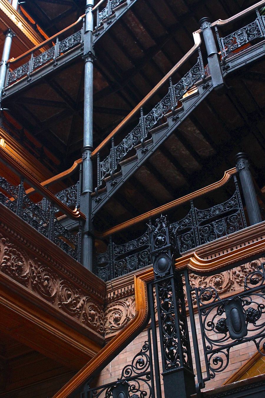 Iron staircases and ornate railings rising through the skylit atrium of the Bradbury Building