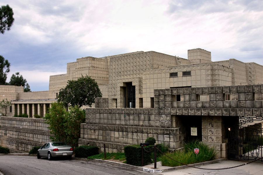 The concrete block mass of the Ennis House rising above a narrow hillside street