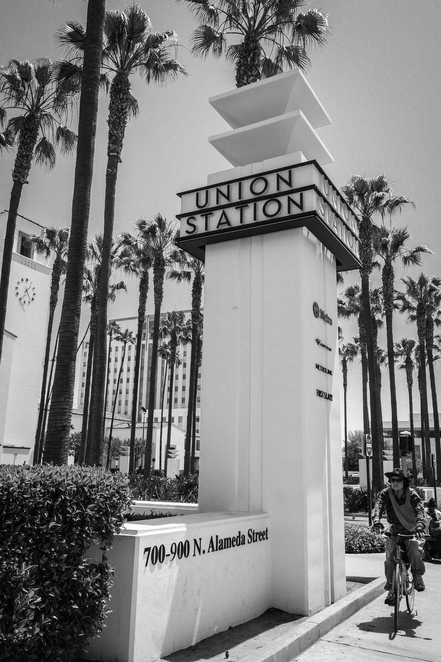 The Union Station name pylon on North Alameda Street with palm trees and the clock tower