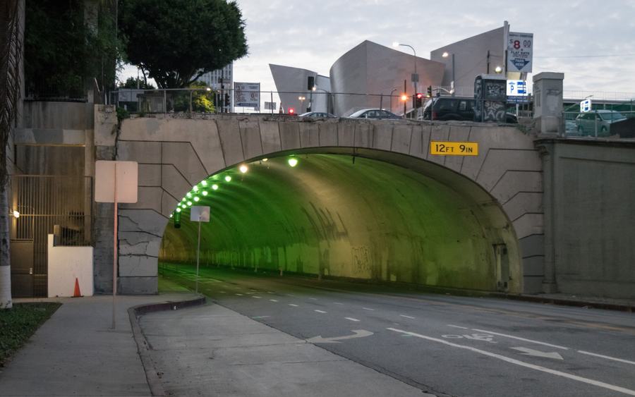 The arched Hill Street entrance of the 2nd Street Tunnel glowing green at dusk