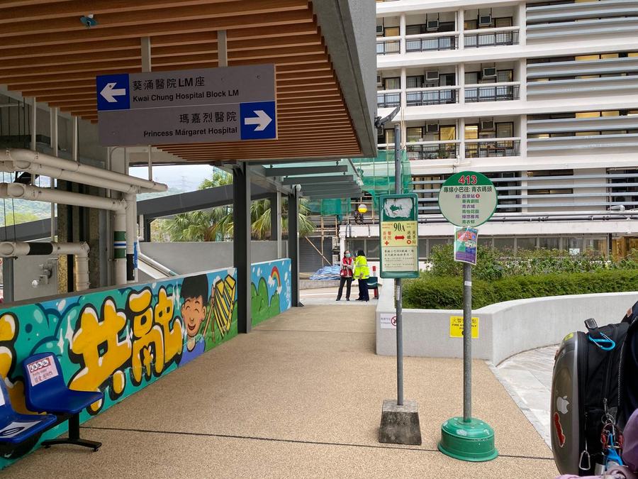 The covered approach to Princess Margaret Hospital in Kwai Chung, Hong Kong: a sign points right to the hospital and left to Kwai Chung Hospital next door. The hospital blocks themselves are behind the camera.