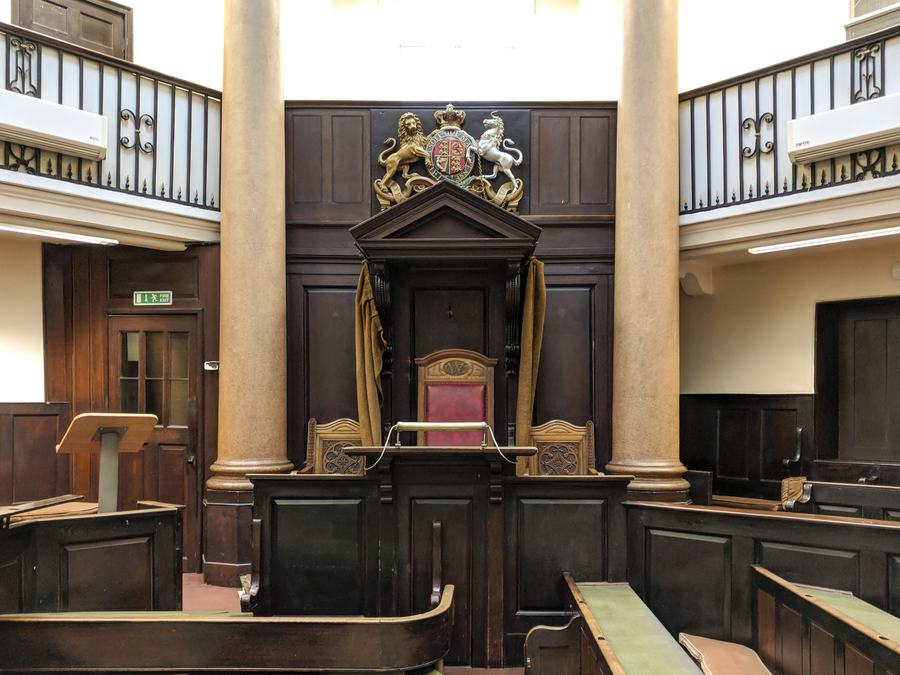 Wood-panelled Georgian court room with royal arms above the judge's chair