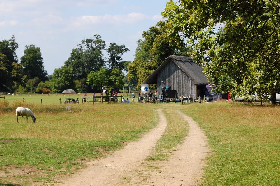 Thatched cricket pavilion at Stanway with a film crew and lighting rigs in front of it