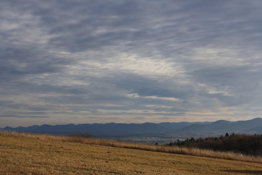 A mown grassy slope with rows of blue Carpathian ridges receding into haze