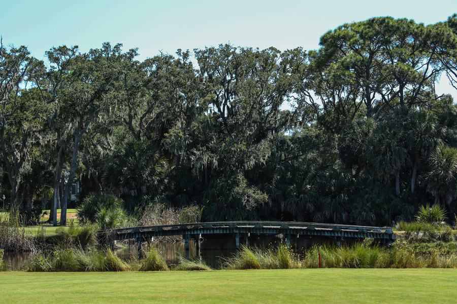 Wooden footbridge crossing a creek on a golf course under live oaks