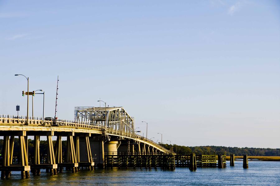 Steel swing bridge across a wide tidal river at dusk