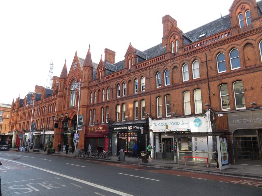 The long red brick Victorian frontage of George's Street Arcade on South Great George's Street, Dublin, with shops along the ground floor.