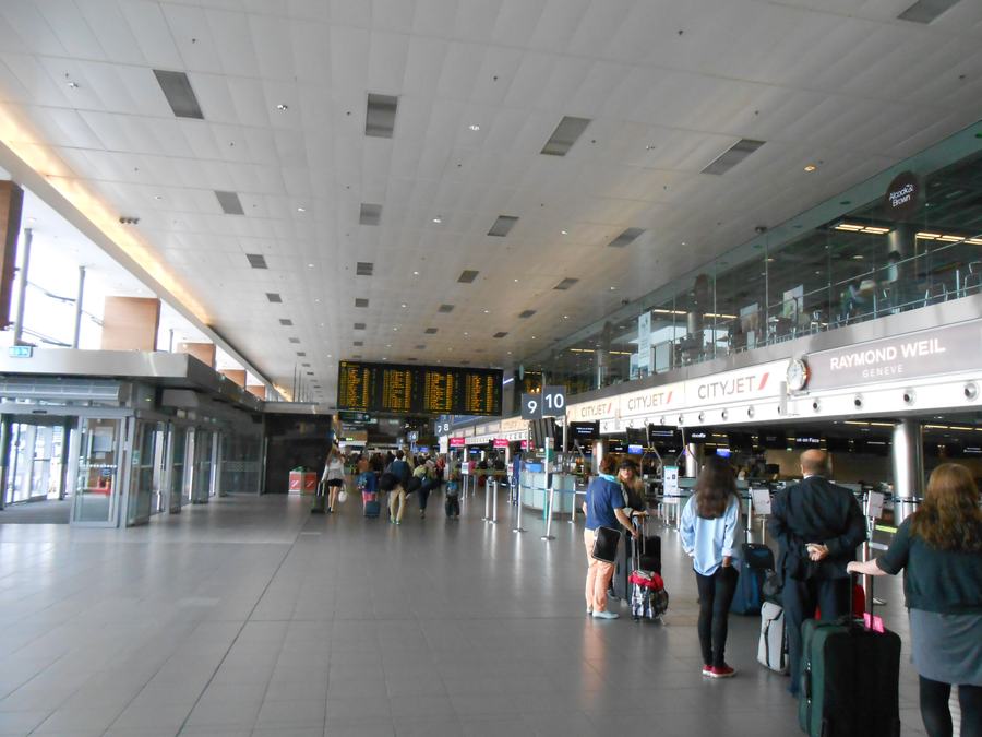 The departures hall at Dublin Airport, with check in desks along one side, departure boards overhead and passengers with luggage.