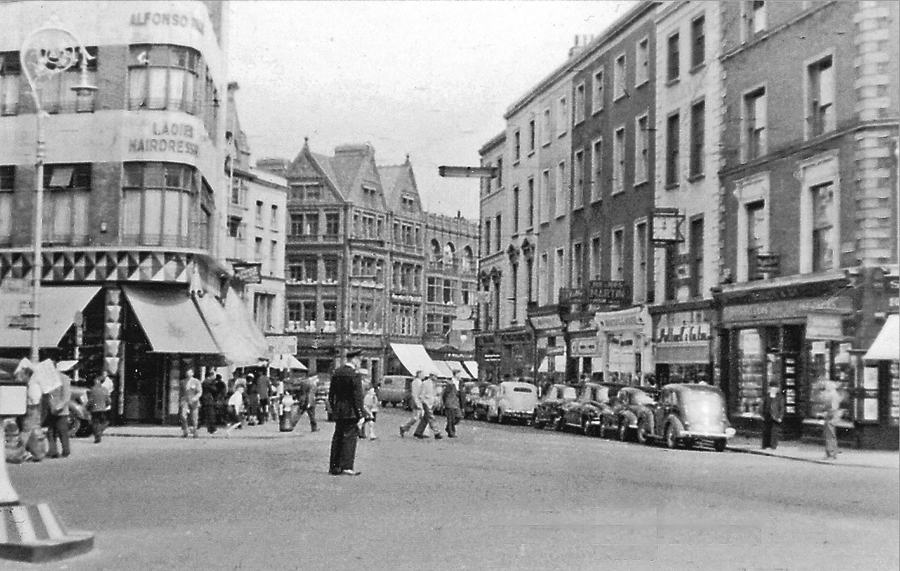 Black and white photograph of Grafton Street, Dublin, in 1955, looking from the St Stephen's Green end past awnings and parked cars.
