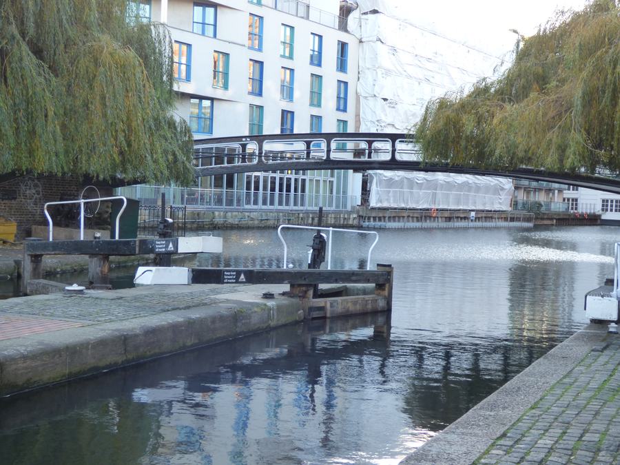 A lock chamber on the Regent's Canal at Camden with an iron roving bridge over it and modern flats behind.
