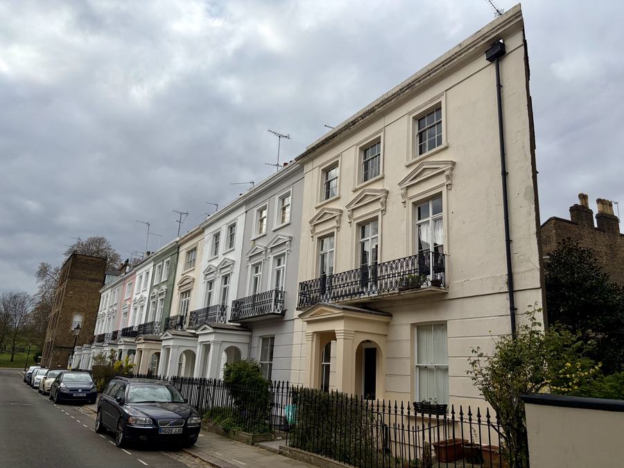 Stucco-fronted terraced houses at 1–17 Chalcot Crescent, Primrose Hill, London, seen along the pavement on a bright day.