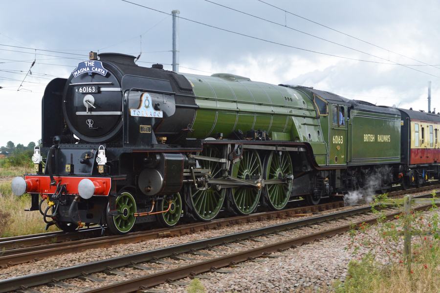 The A1 Pacific locomotive 60163 Tornado in British Railways green, running light engine on a main line under overhead wires.