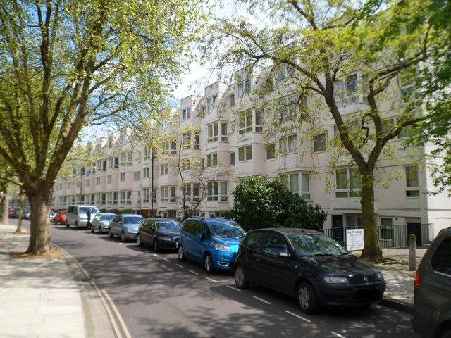 Warwick Crescent, London W2: a row of pale post-war flats behind plane trees, with cars parked along the kerb.