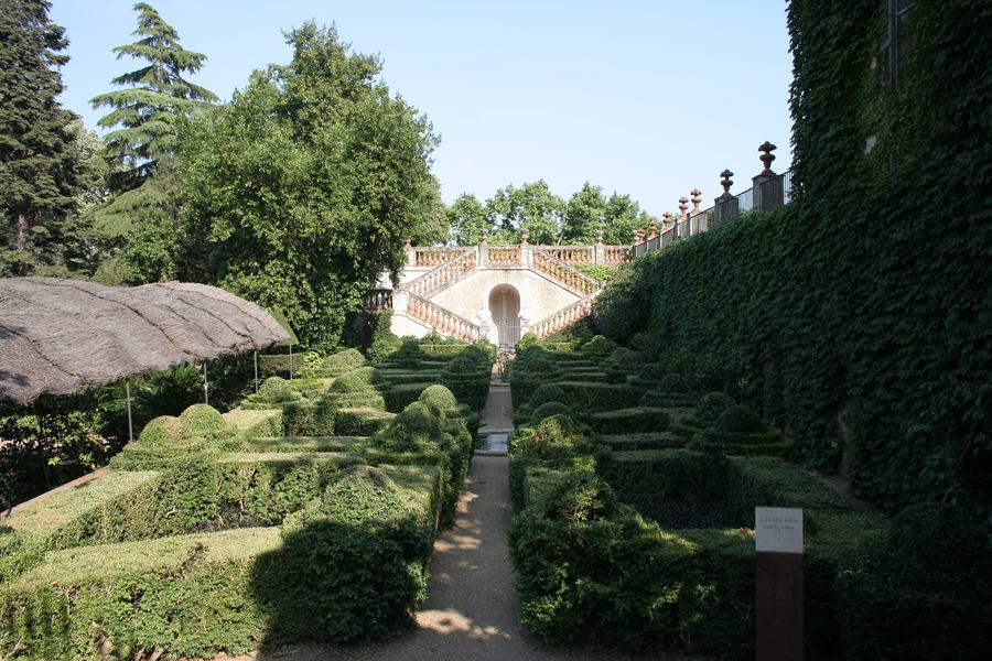 A formal garden of low clipped hedges leading to a balustraded double staircase cut into the hillside.