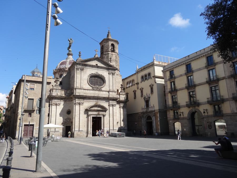 A wide open square with a baroque church front and eighteenth-century town facades, almost empty in strong sunlight.