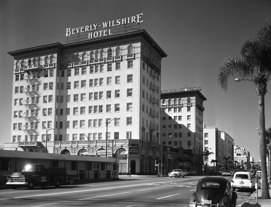 Black and white street view of a large 1920s hotel with a rooftop sign reading Beverly-Wilshire Hotel