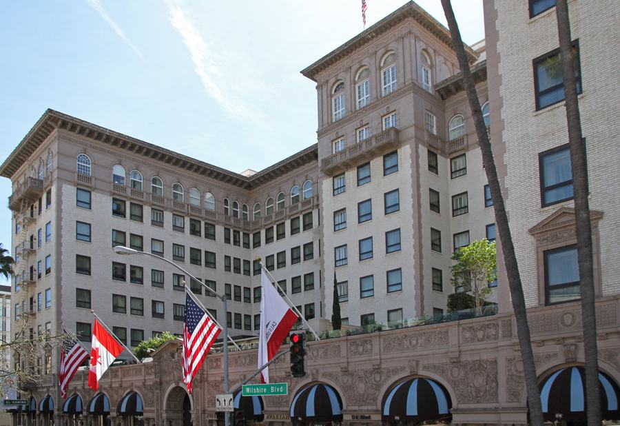 Nine-storey stone hotel with arched windows and awnings, flags over the entrance