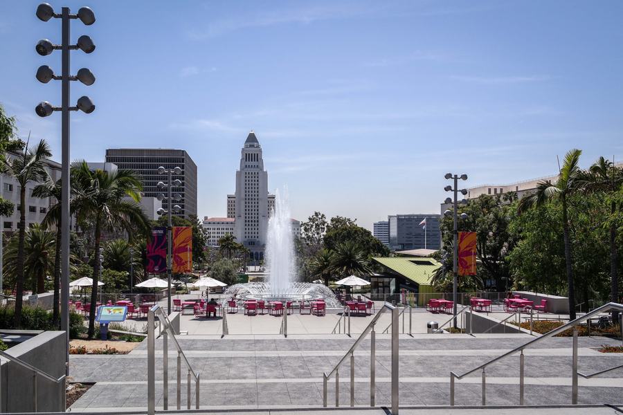 Green park lawns and paths with the tower of Los Angeles City Hall behind