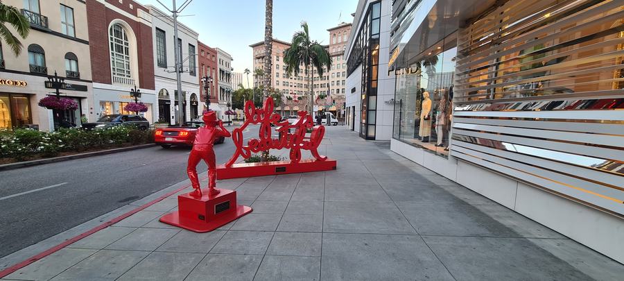 Rodeo Drive pavement with red sculptures, shop windows and a large hotel at the far end
