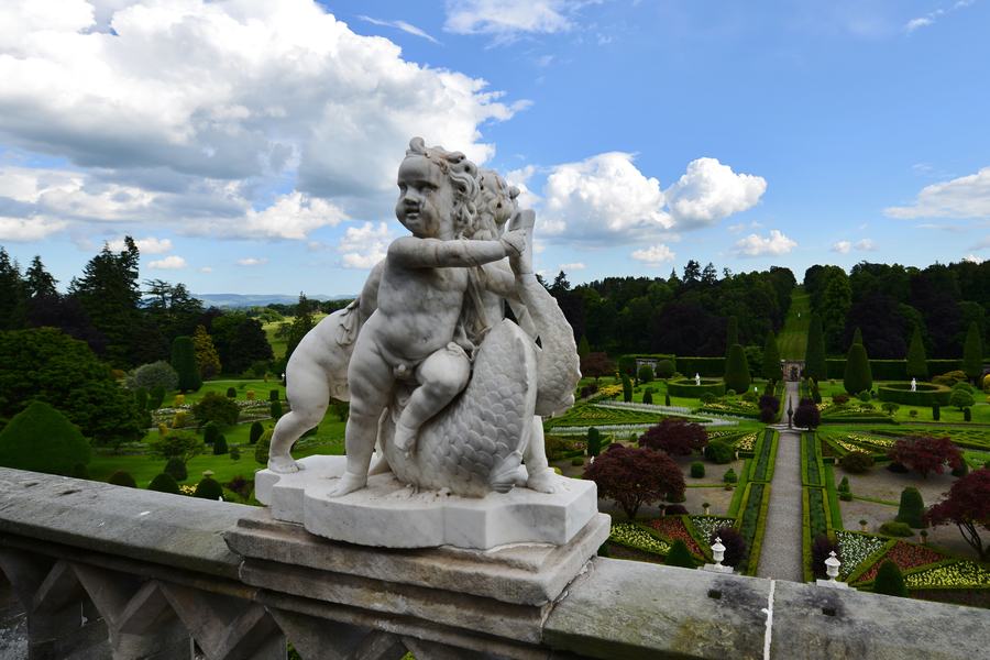 A marble putto on the stone balustrade at Drummond Castle with the formal gardens laid out below