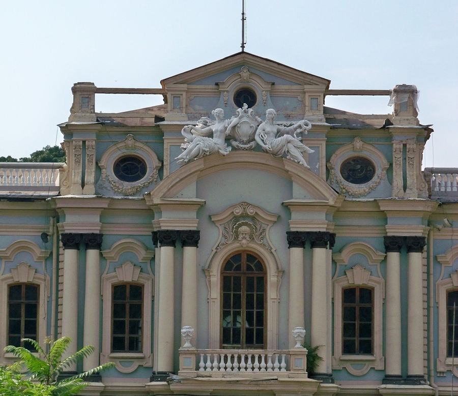 Close view of a baroque palace bay with white stucco cherubs over an arched window