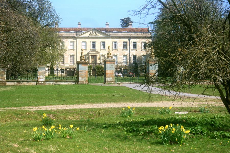 The Palladian west front of Thame Park House seen through iron gates from the park