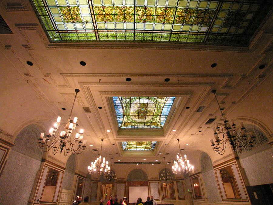 Ballroom interior with a long stained glass ceiling panel, chandeliers and panelled walls