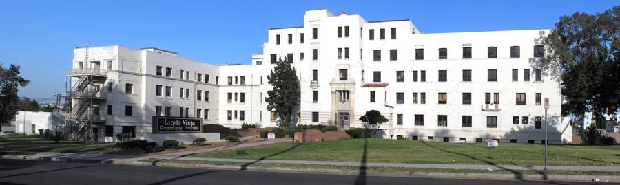 Long white 1930s hospital building with a sign reading Linda Vista Community Hospital on a lawn