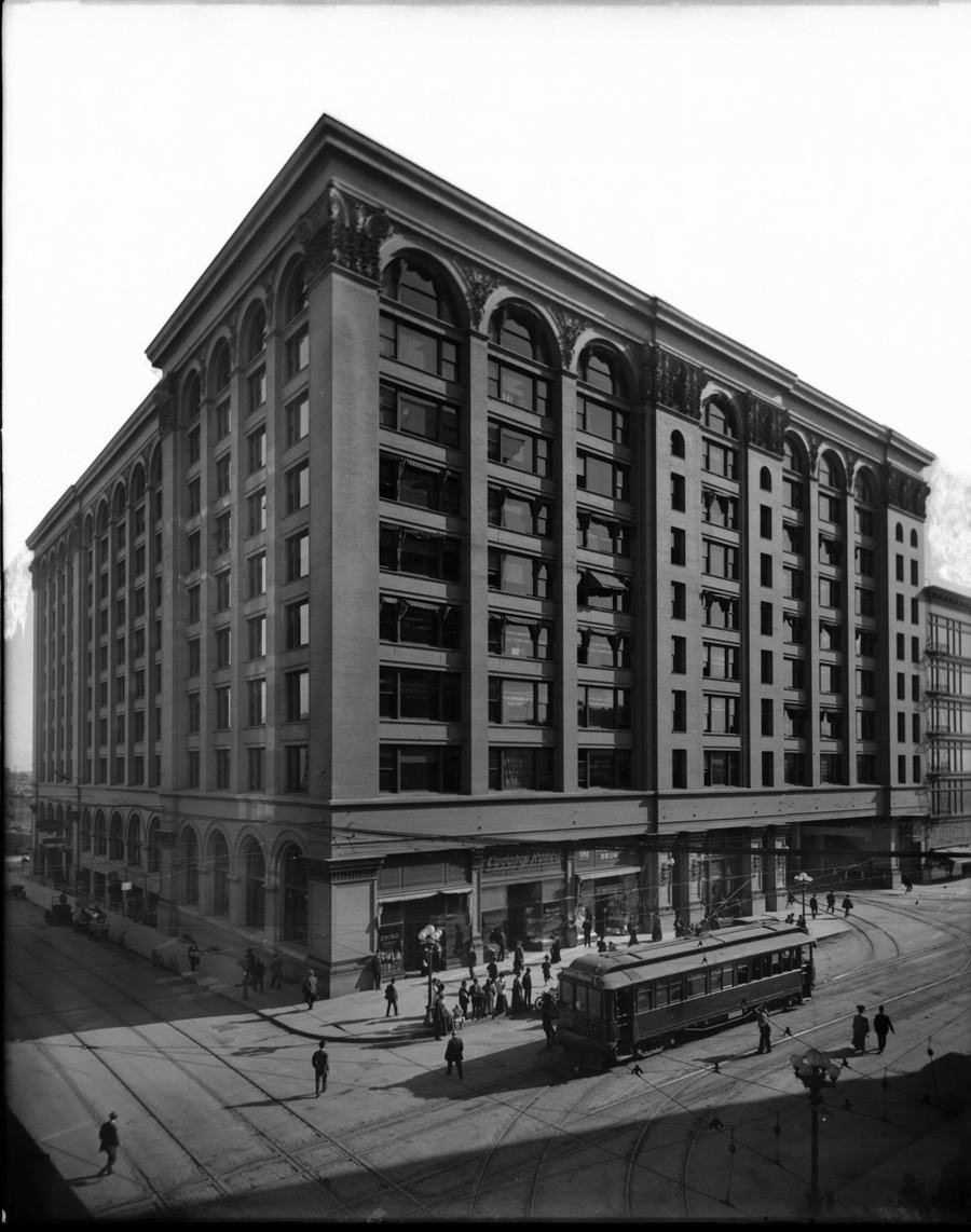 Black and white photograph of the Pacific Electric Building with a streetcar and crowds on the corner in about 1905
