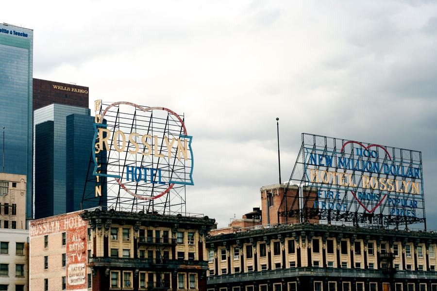 Two rooftop steel sign frames reading Rosslyn Hotel and New Million Dollar Hotel Rosslyn above brick buildings