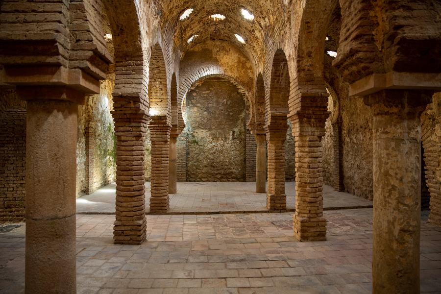 Brick horseshoe arches and columns under a vaulted roof with star-shaped skylights, Arab baths, Ronda