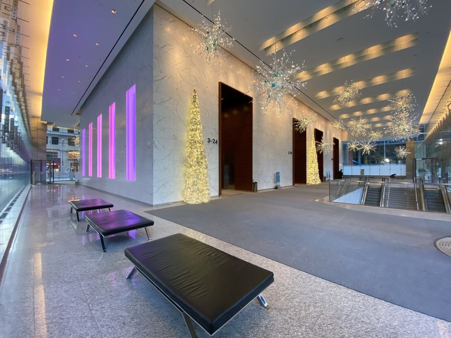 Empty marble lobby of Bay Adelaide West Tower with black benches, purple light panels and Christmas trees