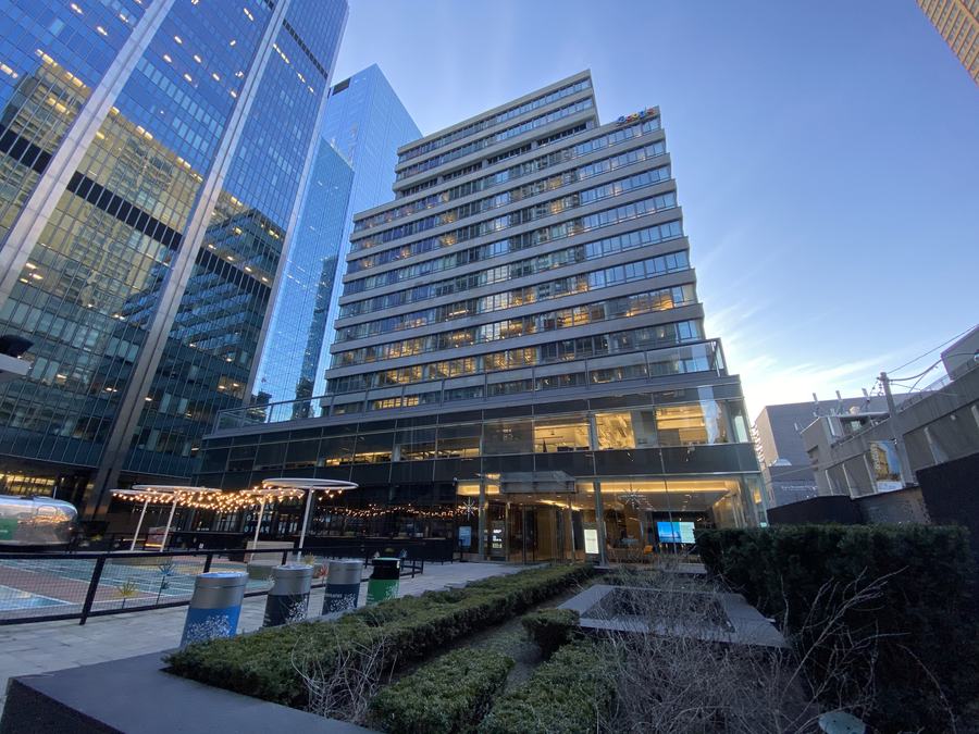 Richmond-Adelaide Centre office building rising above a landscaped courtyard with hedges and string lights, Toronto