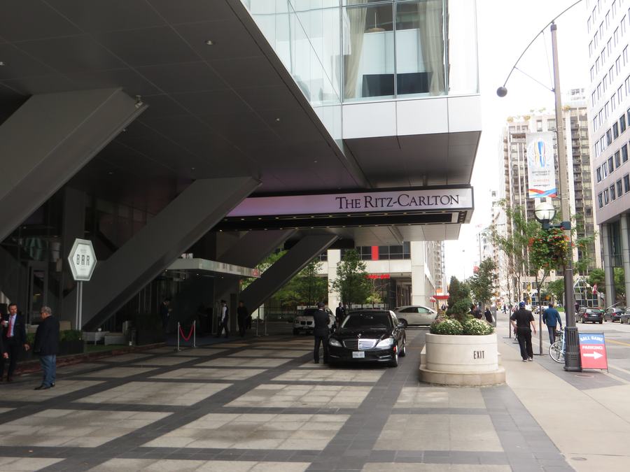 Covered drop-off entrance of The Ritz-Carlton Toronto with the hotel name over the driveway and a black car waiting