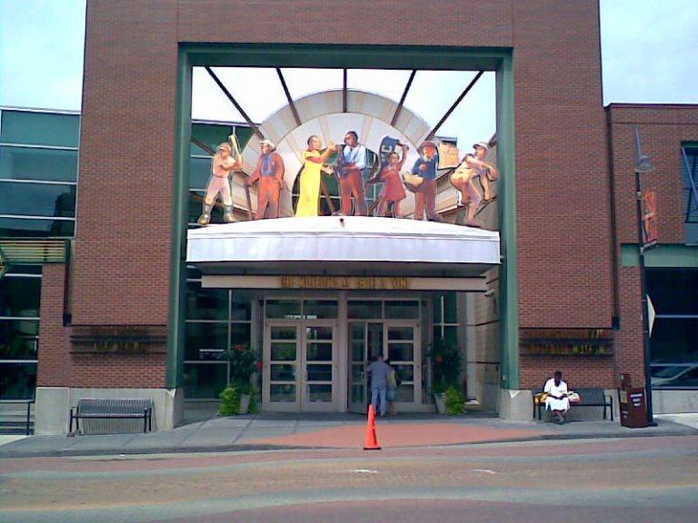 A brick museum entrance on East 18th Street, with a colourful figurative sculpture of ballplayers and musicians above the doors