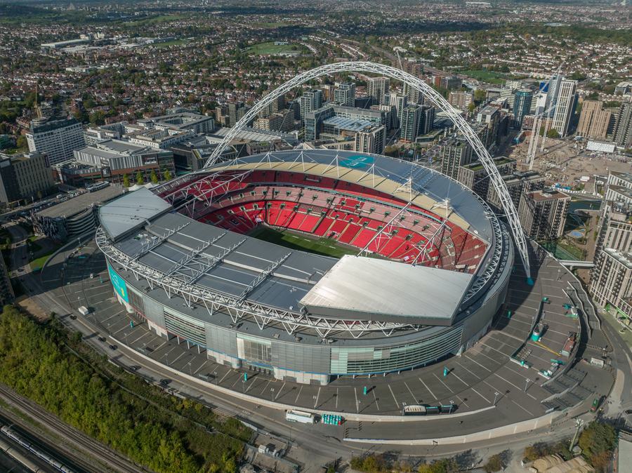 An aerial view of Wembley Stadium with its white arch over the bowl and red seats