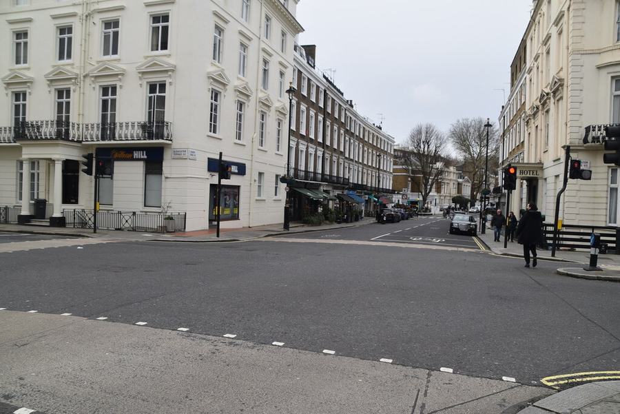 A wide empty London street junction lined with white stucco terraces, a hotel sign on the right-hand corner.